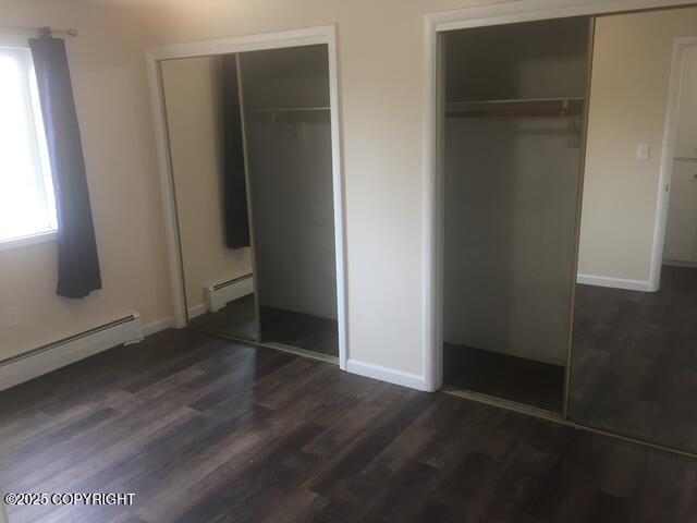 420 E 14th Ave, Anchorage, AK 99501 - unfurnished bedroom with two closets, a baseboard radiator, and dark wood-style flooring