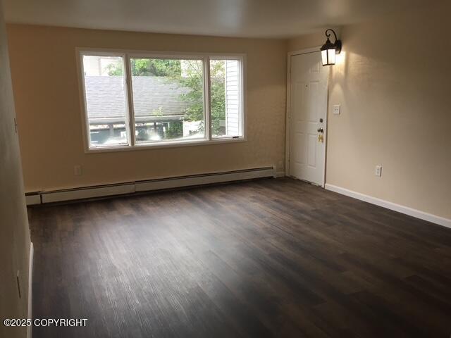 420 E 14th Ave, Anchorage, AK 99501 - unfurnished living room with a baseboard radiator and dark wood-type flooring