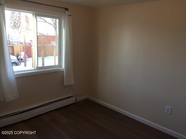420 E 14th Ave, Anchorage, AK 99501 - spare room with a baseboard heating unit and dark wood-style floors