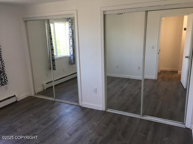 420 E 14th Ave, Anchorage, AK 99501 - unfurnished bedroom with a baseboard heating unit, wood finished floors, and multiple closets