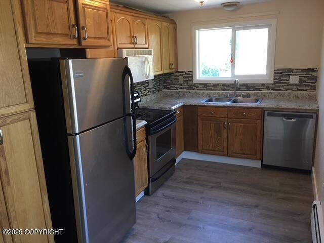 420 E 14th Ave, Anchorage, AK 99501 - kitchen with appliances with stainless steel finishes, backsplash, baseboard heating, and wood finished floors