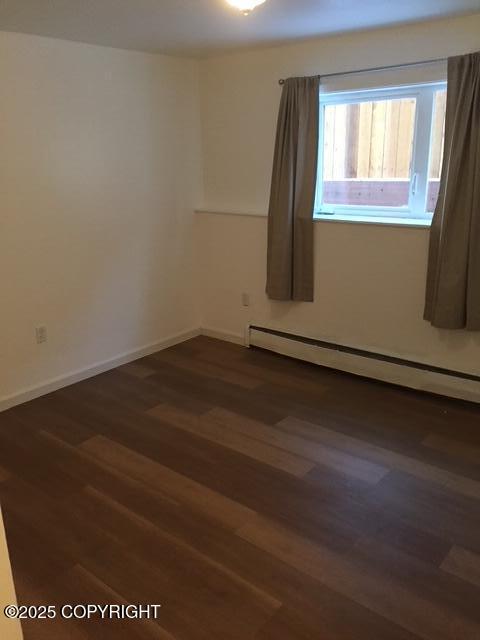 420 E 14th Ave, Anchorage, AK 99501 - empty room featuring a baseboard heating unit and dark wood-style flooring
