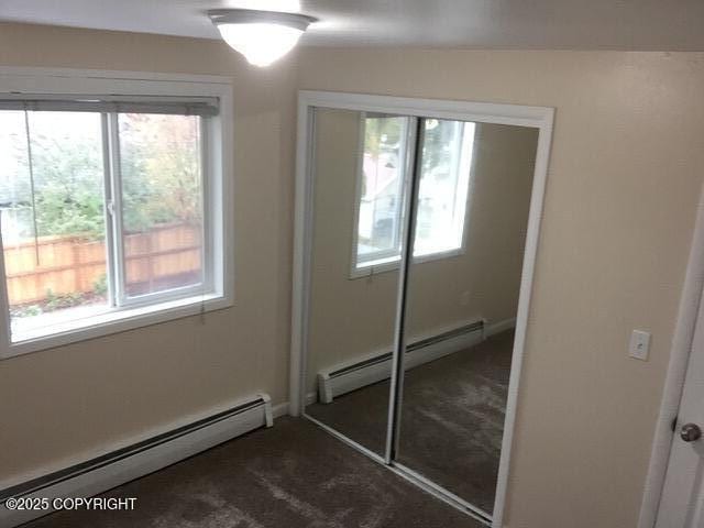 420 E 14th Ave, Anchorage, AK 99501 - unfurnished bedroom with a baseboard radiator, multiple windows, and dark colored carpet