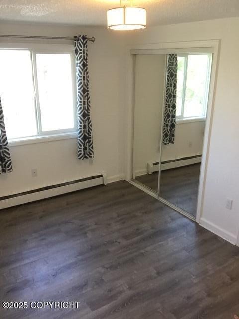 420 E 14th Ave, Anchorage, AK 99501 - unfurnished bedroom with baseboard heating, a closet, and dark wood-type flooring