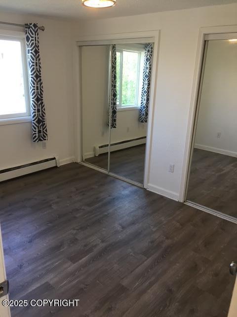 420 E 14th Ave, Anchorage, AK 99501 - unfurnished bedroom featuring a baseboard heating unit and dark wood finished floors