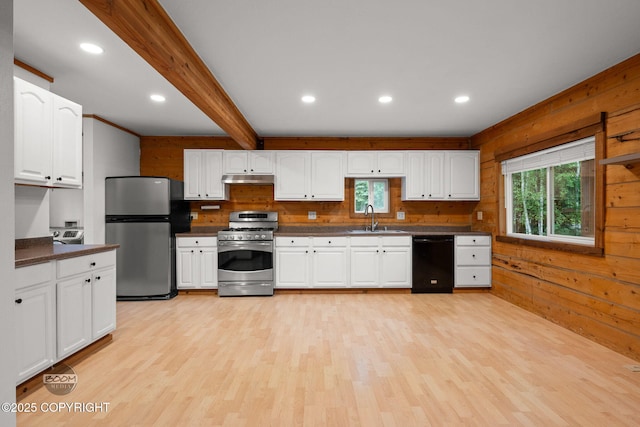 1291 N Rainbow Park Dr, Wasilla, AK 99623 - kitchen with appliances with stainless steel finishes, under cabinet range hood, healthy amount of natural light, dark countertops, and wood walls