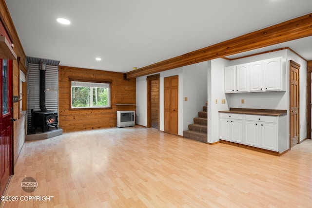 1291 N Rainbow Park Dr, Wasilla, AK 99623 - unfurnished living room with a wood stove, light wood-type flooring, heating unit, wood walls, and stairway