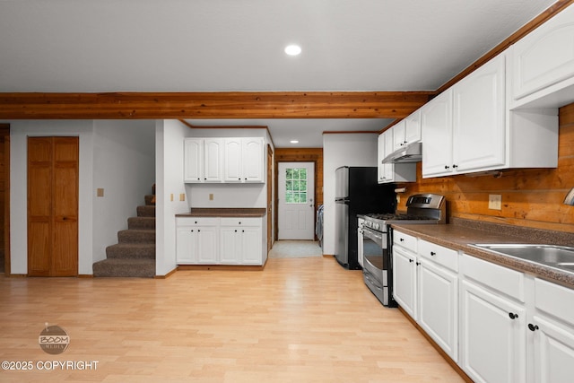 1291 N Rainbow Park Dr, Wasilla, AK 99623 - kitchen with stainless steel appliances, under cabinet range hood, dark countertops, light wood-type flooring, and white cabinets