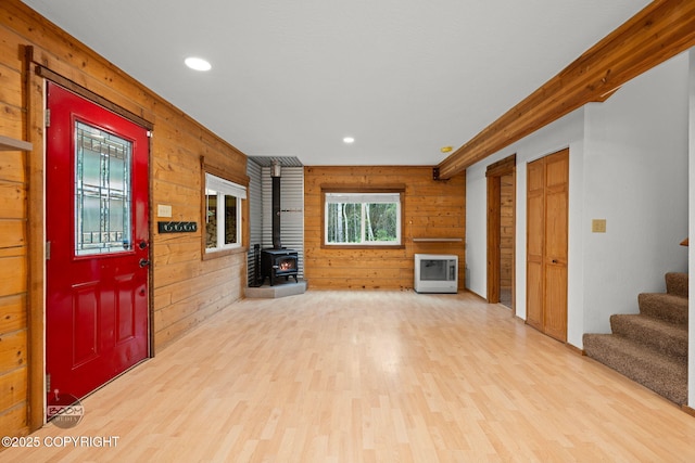 1291 N Rainbow Park Dr, Wasilla, AK 99623 - unfurnished living room with wood walls, a wood stove, heating unit, light wood-type flooring, and stairway