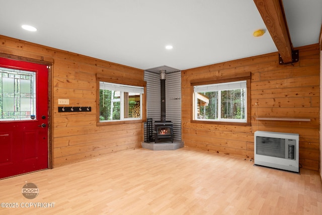 1291 N Rainbow Park Dr, Wasilla, AK 99623 - unfurnished living room with heating unit, a wood stove, healthy amount of natural light, light wood-style flooring, and wooden walls