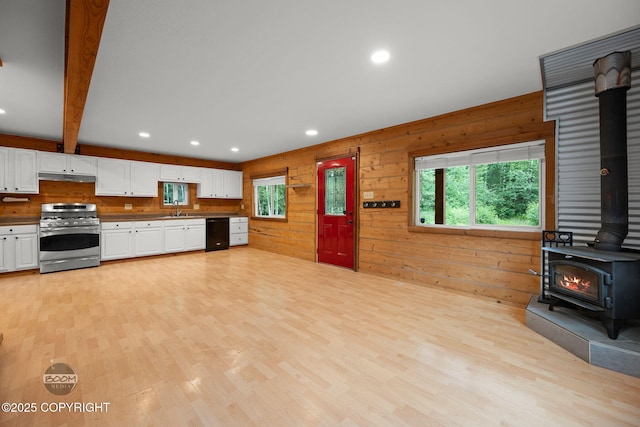 1291 N Rainbow Park Dr, Wasilla, AK 99623 - kitchen with stainless steel gas range oven, a wood stove, dishwasher, white cabinets, and wooden walls