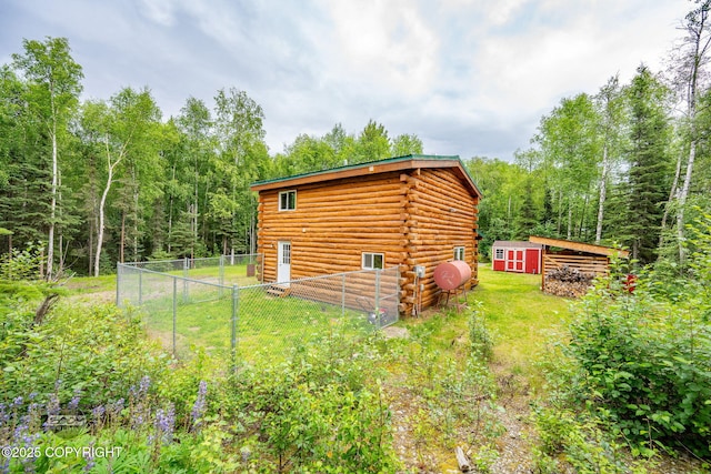 1291 N Rainbow Park Dr, Wasilla, AK 99623 - view of side of home with log siding, a view of trees, and a storage shed