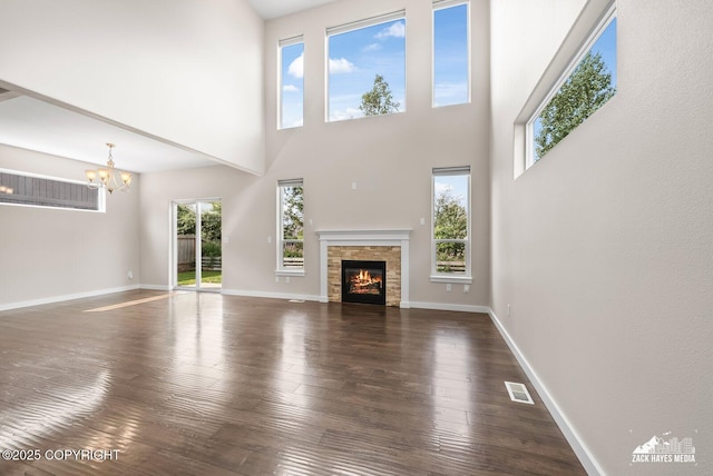 8126 Grayhawk Cir, Anchorage, AK 99507 - unfurnished living room with a chandelier, wood-type flooring, a stone fireplace, and a high ceiling