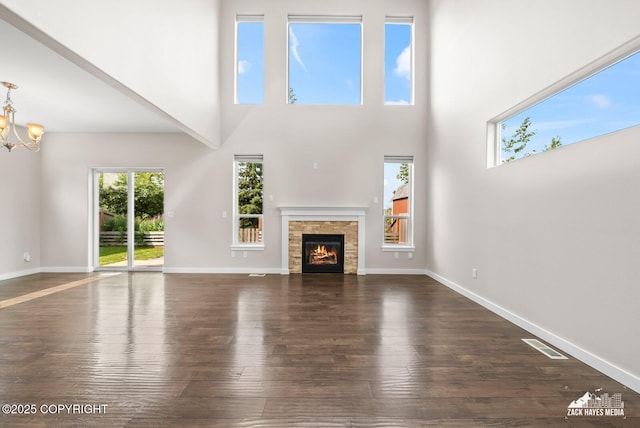 8126 Grayhawk Cir, Anchorage, AK 99507 - unfurnished living room with dark wood-style floors, a chandelier, a warm lit fireplace, and a high ceiling