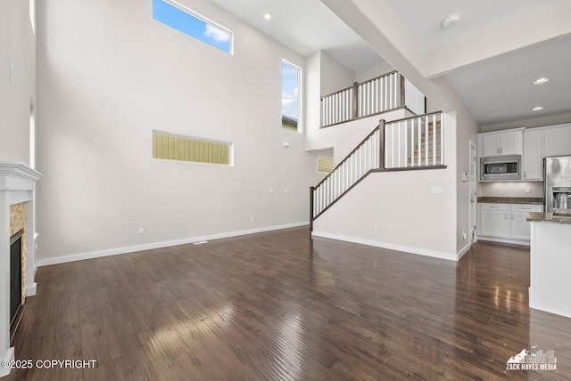 8126 Grayhawk Cir, Anchorage, AK 99507 - unfurnished living room with stairway, a stone fireplace, a high ceiling, dark wood finished floors, and recessed lighting