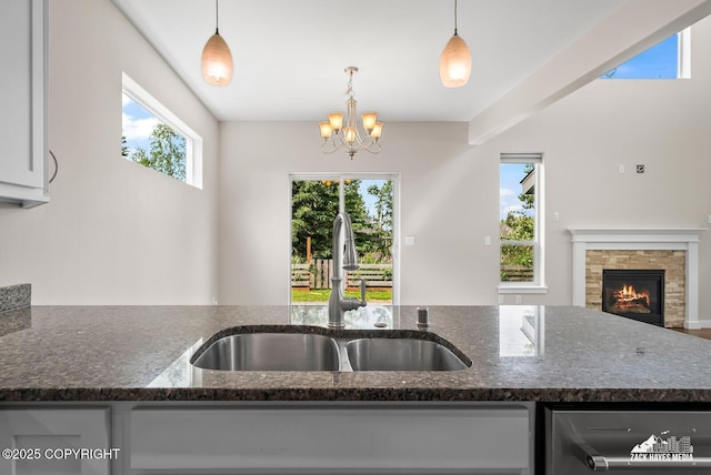 8126 Grayhawk Cir, Anchorage, AK 99507 - kitchen with dishwasher, dark stone counters, a stone fireplace, a chandelier, and decorative light fixtures