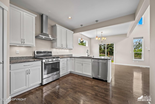 8126 Grayhawk Cir, Anchorage, AK 99507 - kitchen with stainless steel appliances, wall chimney exhaust hood, a peninsula, a chandelier, and dark wood-type flooring