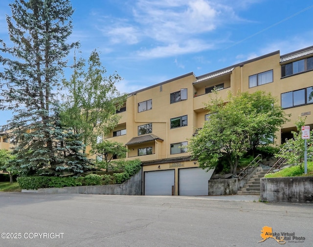 1201 Denali St Unit 210, Anchorage, AK 99501 - view of apartment building / complex featuring stairs and an attached garage