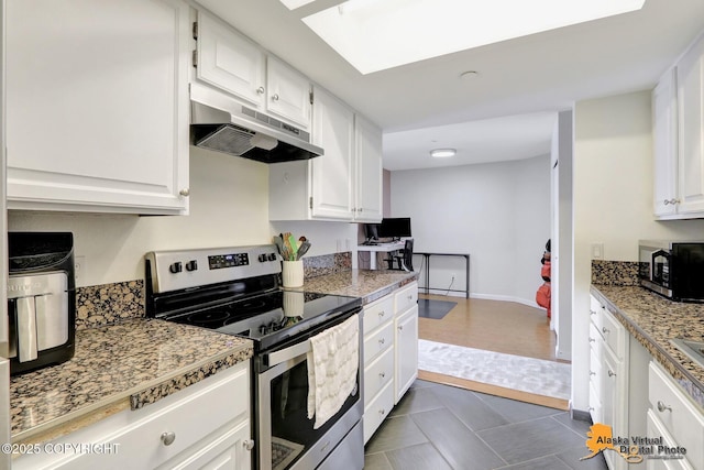 1201 Denali St Unit 210, Anchorage, AK 99501 - kitchen with appliances with stainless steel finishes, under cabinet range hood, white cabinets, dark tile patterned floors, and light countertops