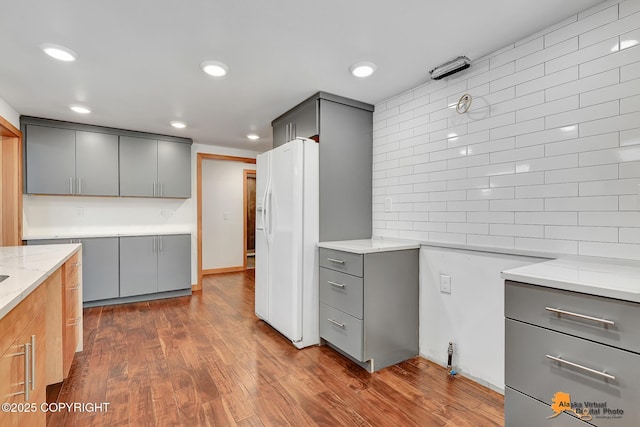 2641 W 27th Ave, Anchorage, AK 99517 - kitchen with gray cabinets, white refrigerator with ice dispenser, light stone countertops, dark wood finished floors, and recessed lighting