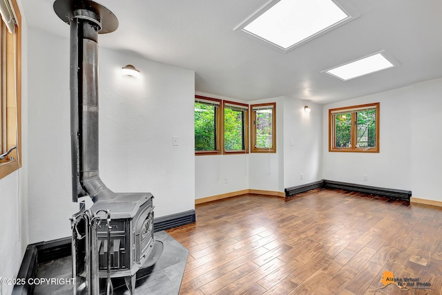 2641 W 27th Ave, Anchorage, AK 99517 - spare room with a wood stove, plenty of natural light, wood finished floors, and baseboard heating