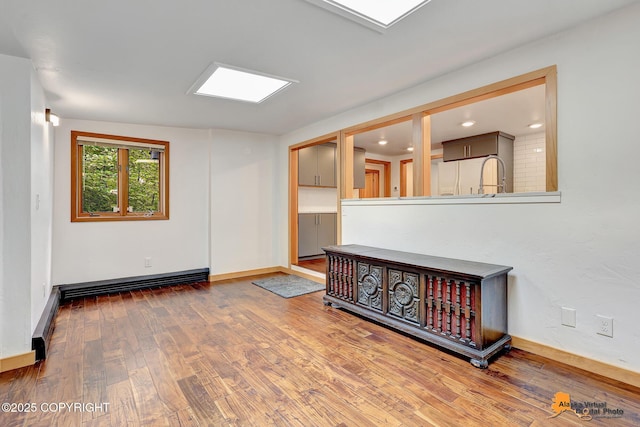 2641 W 27th Ave, Anchorage, AK 99517 - unfurnished living room with wood finished floors, a baseboard heating unit, and recessed lighting