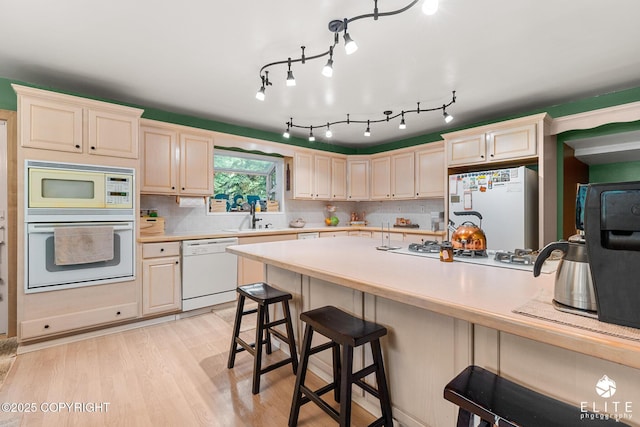 22432 Glacier View Dr, Eagle River, AK 99577 - kitchen featuring white appliances, a kitchen bar, light countertops, light wood-type flooring, and decorative backsplash