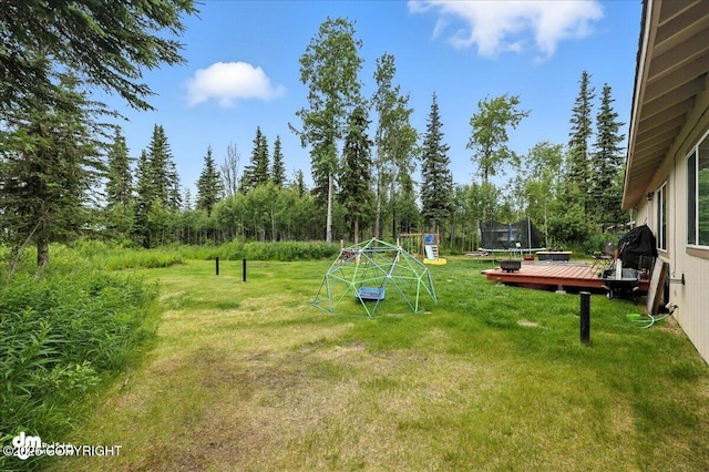 34443 Matanuska St, Soldotna, AK 99669 - view of green lawn with a trampoline, a wooden deck, and a playground