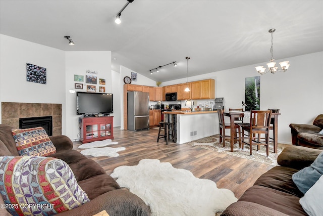 5586 Sapphire Loop # 55B, Anchorage, AK 99504 - living area with lofted ceiling, a chandelier, wood finished floors, rail lighting, and a tile fireplace