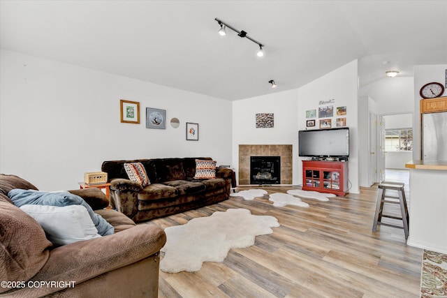 5586 Sapphire Loop # 55B, Anchorage, AK 99504 - living room featuring light wood-style flooring, vaulted ceiling, track lighting, and a tile fireplace