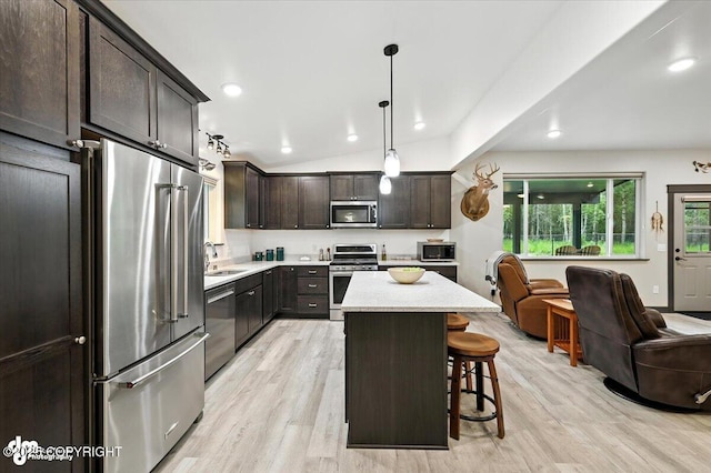 5551 N Wildwood Dr, Wasilla, AK 99654 - kitchen with stainless steel appliances, light wood-type flooring, dark brown cabinetry, a breakfast bar, and open floor plan