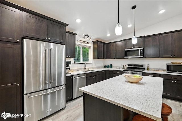 5551 N Wildwood Dr, Wasilla, AK 99654 - kitchen with stainless steel appliances, dark brown cabinets, light wood-style floors, a kitchen island, and pendant lighting
