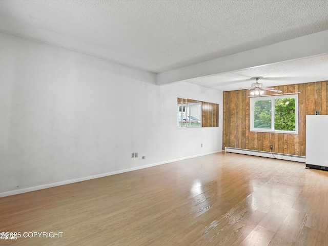 9801 Whitefish Cir, Anchorage, AK 99515 - spare room featuring a baseboard radiator, wood finished floors, a ceiling fan, a textured ceiling, and wooden walls