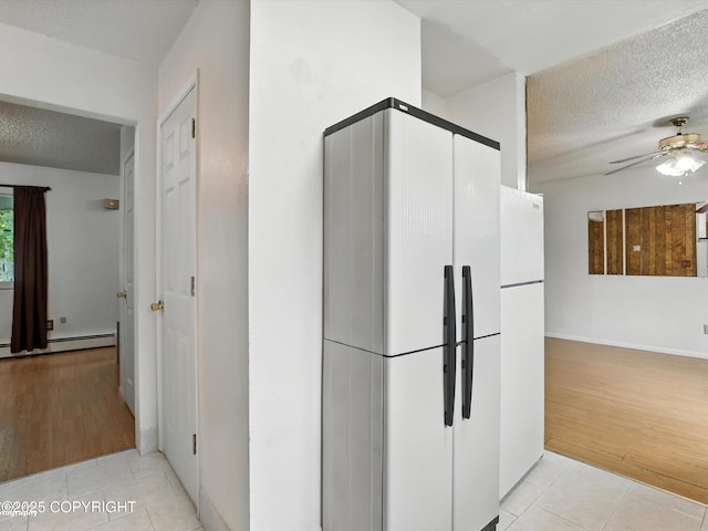 9801 Whitefish Cir, Anchorage, AK 99515 - kitchen with freestanding refrigerator, light tile patterned flooring, a textured ceiling, and a baseboard heating unit