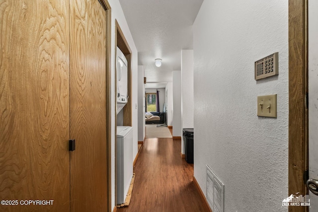 8641 Blackberry St # 6B, Anchorage, AK 99502 - hall with stacked washer / dryer, dark wood-style floors, and a textured wall