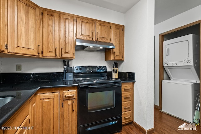 8641 Blackberry St # 6B, Anchorage, AK 99502 - kitchen featuring black electric range oven, under cabinet range hood, stacked washer and clothes dryer, dark wood-type flooring, and brown cabinetry