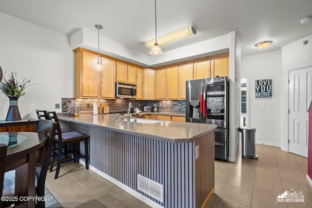 7655 Stepping Stone Ln Unit Q2, Anchorage, AK 99504 - kitchen featuring appliances with stainless steel finishes, backsplash, light tile patterned flooring, a peninsula, and decorative light fixtures