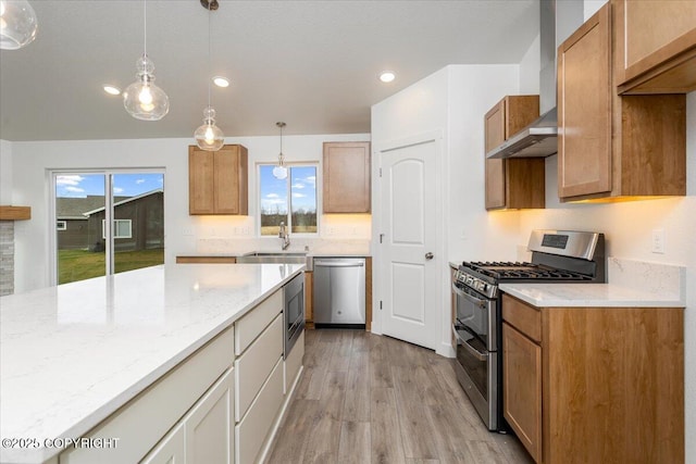 4125 E Zircon Cir, Wasilla, AK 99654 - kitchen with stainless steel appliances, wall chimney exhaust hood, light wood finished floors, light stone countertops, and decorative light fixtures