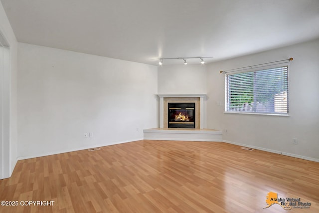 2321 Lusardi Point Cir, Anchorage, AK 99515 - unfurnished living room featuring rail lighting, wood finished floors, and a glass covered fireplace