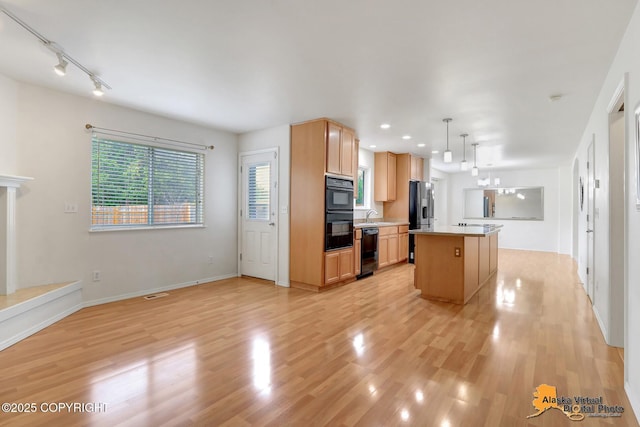 2321 Lusardi Point Cir, Anchorage, AK 99515 - kitchen with black appliances, light wood finished floors, a center island, light countertops, and open floor plan