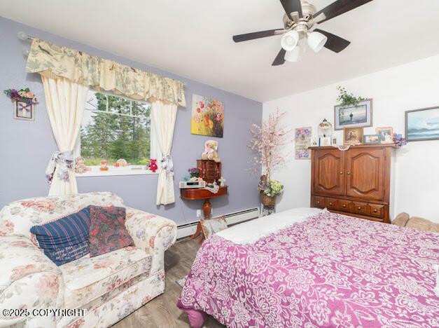 282 Marydale Ct, Soldotna, AK 99669 - bedroom with light wood finished floors, a baseboard heating unit, and ceiling fan