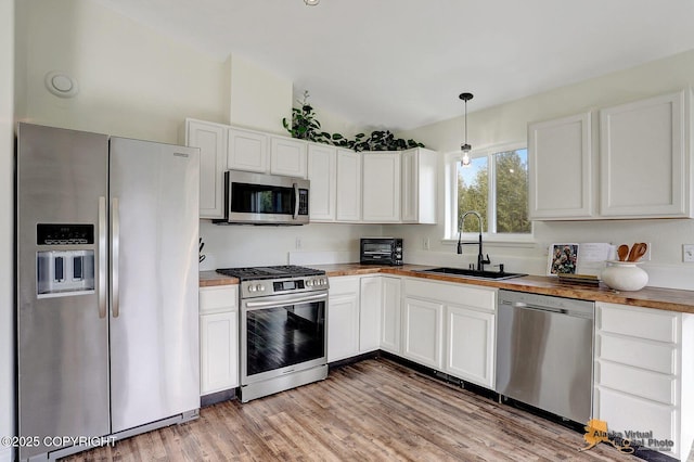 14795 E Hearthstone Dr, Palmer, AK 99645 - kitchen with stainless steel appliances, lofted ceiling, white cabinets, light wood finished floors, and decorative light fixtures