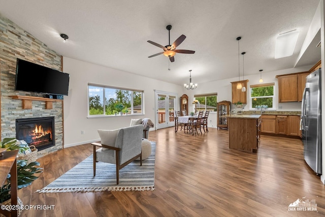 23011 Sherman St # 24, Chugiak, AK 99567 - living room with ceiling fan, a stone fireplace, dark wood-style flooring, a chandelier, and a textured ceiling