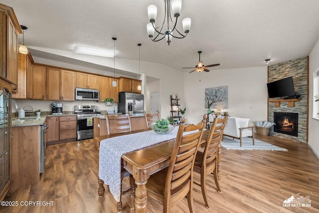 23011 Sherman St # 24, Chugiak, AK 99567 - dining area with a stone fireplace, wood finished floors, ceiling fan, a chandelier, and lofted ceiling