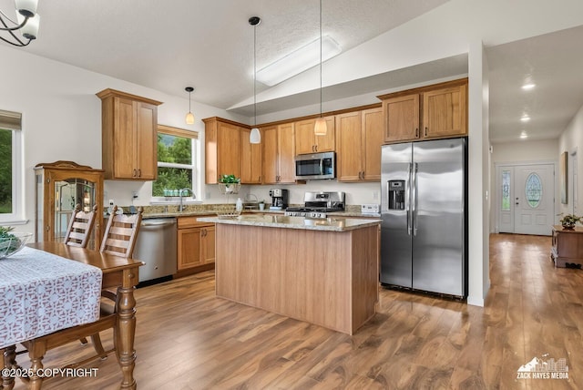 23011 Sherman St # 24, Chugiak, AK 99567 - kitchen with stainless steel appliances, vaulted ceiling, a kitchen island, wood finished floors, and light stone counters