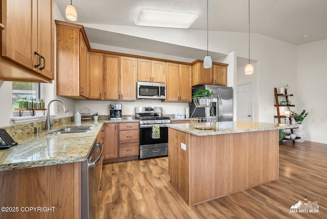 23011 Sherman St # 24, Chugiak, AK 99567 - kitchen featuring stainless steel appliances, vaulted ceiling, wood finished floors, a kitchen island, and decorative light fixtures