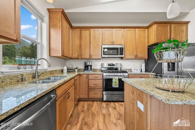 23011 Sherman St # 24, Chugiak, AK 99567 - kitchen featuring stainless steel appliances, light wood-style flooring, light stone counters, vaulted ceiling, and brown cabinetry