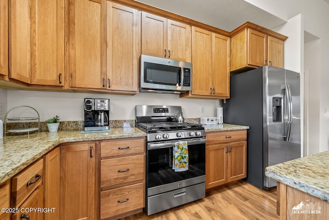 23011 Sherman St # 24, Chugiak, AK 99567 - kitchen with appliances with stainless steel finishes, light wood finished floors, and light stone countertops