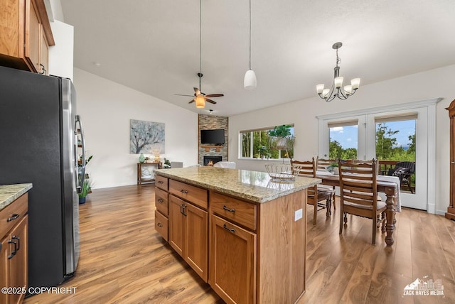 23011 Sherman St # 24, Chugiak, AK 99567 - kitchen featuring freestanding refrigerator, light wood-type flooring, vaulted ceiling, hanging light fixtures, and a fireplace