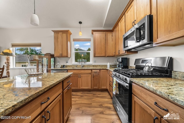23011 Sherman St # 24, Chugiak, AK 99567 - kitchen with appliances with stainless steel finishes, brown cabinetry, hanging light fixtures, and light stone counters